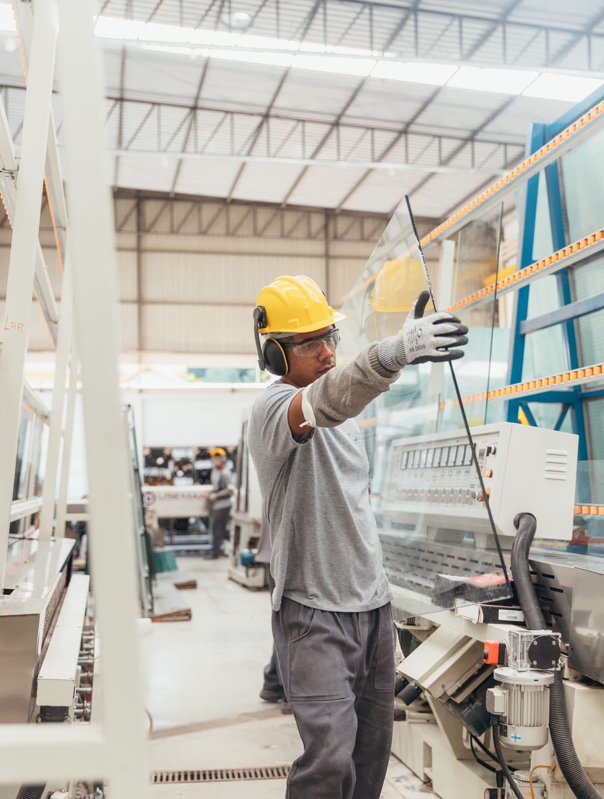 Two workers in hi-vis and hard hats on a factory floor